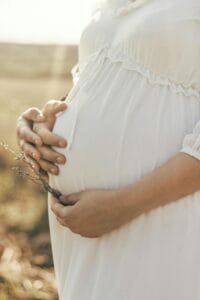 Femme enceinte tenant délicatement son ventre rond, scène douce et lumineuse